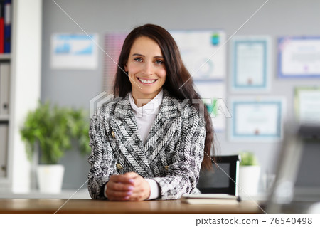 Portrait of a smiling businesswoman at her working table in office Portrait of a smiling businesswoman at her working table in office 76540498