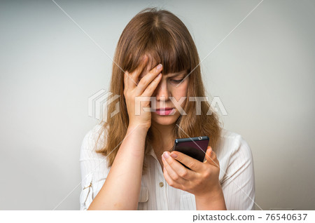 Disappointed woman holding and looking on mobile phone Disappointed woman holding and looking on mobile phone 76540637