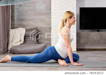 calm future mom-to-be, pregnant female in sportive clothes doing exercises on fitness mat calm future mom-to-be, pregnant female in sportive clothes doing exercises on fitness mat 76541613