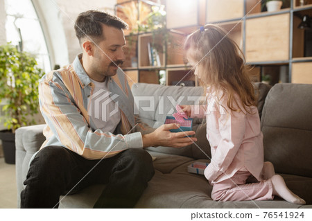 Happy father and little cute daughter at home. Family time, togehterness, parenting and happy childhood concept. Weekend with sincere emotions. 76541924