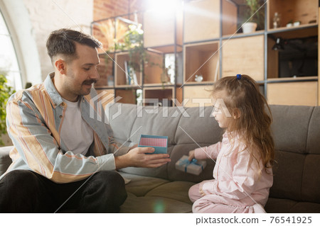 Happy father and little cute daughter at home. Family time, togehterness, parenting and happy childhood concept. Weekend with sincere emotions. 76541925