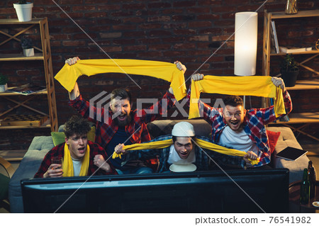 Group of friends watching TV, sport match together. Emotional fans cheering for favourite team, watching on exciting game. Concept of friendship, leisure activity, emotions 76541982