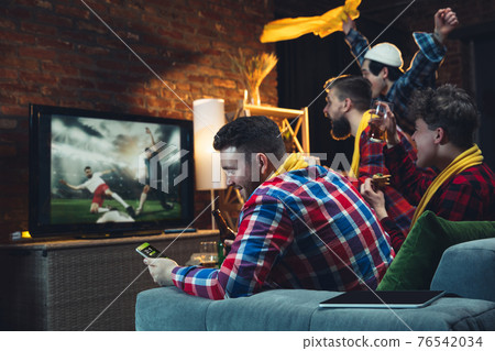 Group of friends watching TV, sport match together. Emotional fans cheering for favourite team, watching on exciting game. Concept of friendship, leisure activity, emotions 76542034