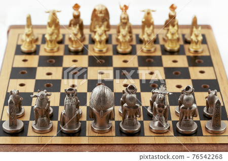 Chess board with placed chess pieces stylized as Egyptian gods 76542268