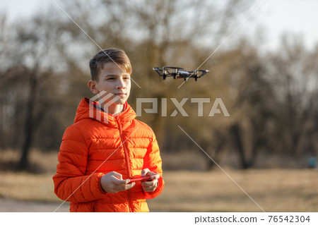 Teenage boy flying small drone in the park Teenage boy flying small drone in the park 76542304