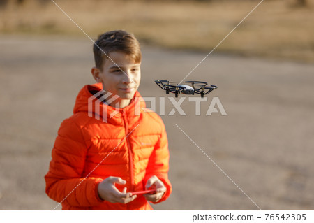 Teenage boy flying small drone in the park 76542305