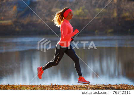 Young sporty woman running along the pond Young sporty woman running along the pond 76542311