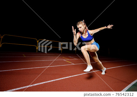 Female track runner bursting off starting block Female track runner bursting off starting block 76542312