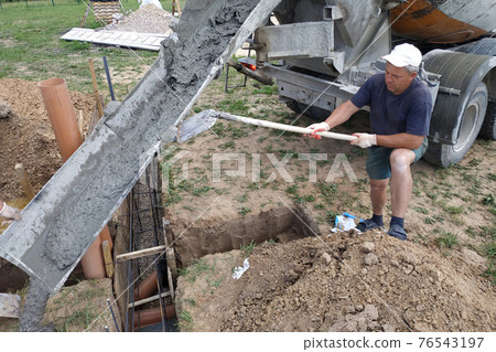 pouring cement into the trench with a mixer, construction work in the summer. pouring cement into the trench with a mixer, construction work in the summer. 76543197