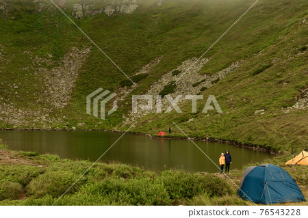Two boys are standing by the water, two brothers are looking at the lake, the reflection in the water, the alpine lake Brebeneskul. 76543228