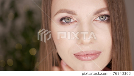 Beauty woman face with green eyes looking at camera. Skin care treatment or cosmetic ads concept. Beautiful female model with perfect fresh and clean skin. Nude make-up. In studio. 76543363