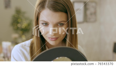 A young woman looks in the mirror, preens herself, admires herself, straightening her clothes and hairstyle. Smiles and likes herself. Start to new day, enjoying morning. Beauty salon makeup A young woman looks in the mirror, preens herself, admires herself, straightening her clothes and hairstyle. Smiles and likes herself. Start to new day, enjoying morning. Beauty salon makeup 76543370