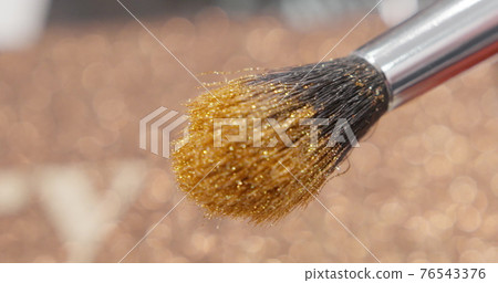 Brush gains glitter to be used in make-up. Macro view of working process, tools in beauty industry. Fashion glamour shiny glitter concept. Brush gains glitter to be used in make-up. Macro view of working process, tools in beauty industry. Fashion glamour shiny glitter concept. 76543376