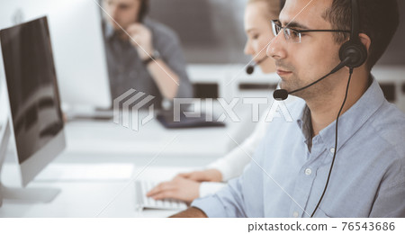 Call center. Group of casual dressed operators at work. Adult businessman in headset at customer service office. Telesales in business Call center. Group of casual dressed operators at work. Adult businessman in headset at customer service office. Telesales in business 76543686