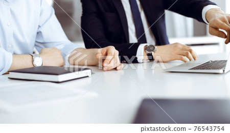 Unknown business people using laptop computer at the desk in modern office. Businessman or male entrepreneur is working with his colleague. Teamwork and partnership concept 76543754