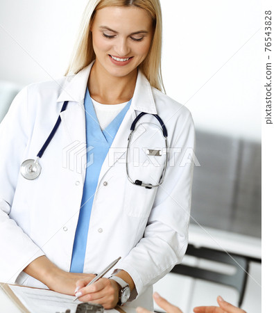 Doctor woman at work in hospital excited and happy of consulting female patient. Blonde physician controls medication history records and exam results while using clipboard. Medicine and healthcare Doctor woman at work in hospital excited and happy of consulting female patient. Blonde physician controls medication history records and exam results while using clipboard. Medicine and healthcare 76543828