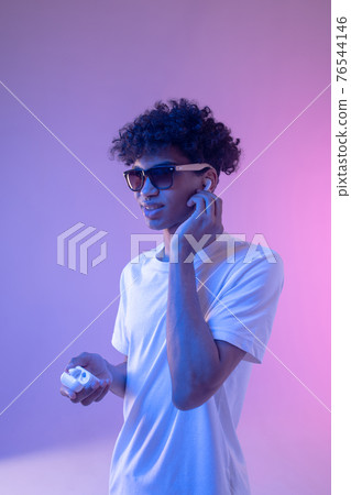 Young mulatto guy in headphones and in sunglasses looking stylish 76544146