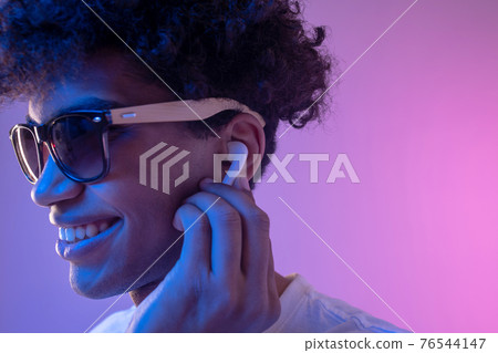 Young mulatto guy in headphones and in sunglasses looking stylish 76544147