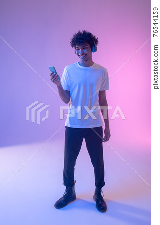 Dark-skinned guy listening to an audio blog online 76544159