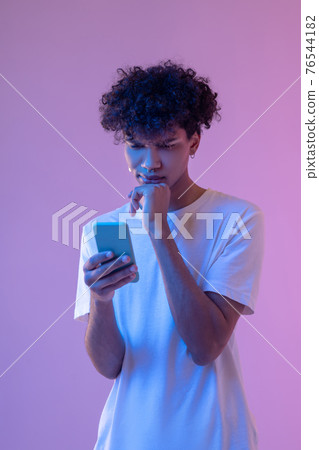 African american guy reading a message on a smartphone 76544182