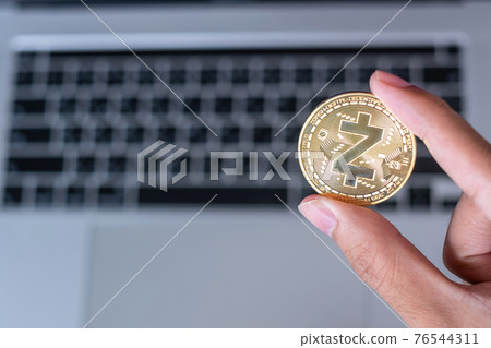 Businessman hand holding Golden Zcash (ZEC) cryptocurrency coin over laptop keyboard, Crypto is Digital Money within the blockchain network, is using technology and online internet exchange. 76544311
