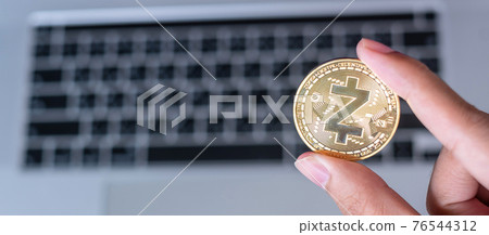Businessman hand holding Golden Zcash (ZEC) cryptocurrency coin over laptop keyboard, Crypto is Digital Money within the blockchain network, is using technology and online internet exchange. 76544312