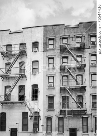 Black and white picture of old buildings with iron fire escapes, New York City, USA. Black and white picture of old buildings with iron fire escapes, New York City, USA. 76544436