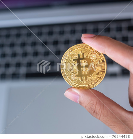 Businessman hand holding golden Bitcoin (BTC) cryptocurrency over laptop keyboard, Crypto is Digital Money within the blockchain network, is exchanged using technology and online exchange concept Businessman hand holding golden Bitcoin (BTC) cryptocurrency over laptop keyboard, Crypto is Digital Money within the blockchain network, is exchanged using technology and online exchange concept 76544458