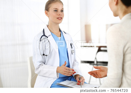 Woman - doctor consults her female patient in sunny clinic 76544720