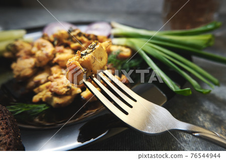 A slice of fried chicken at the end of a fork 76544944