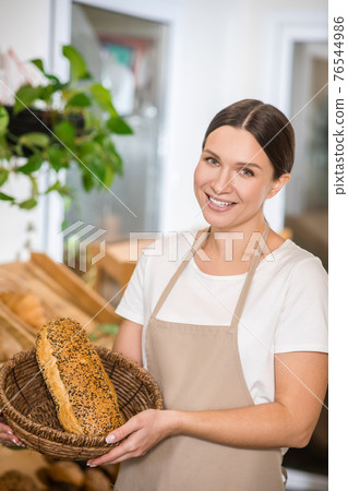 Pretty woman showing bread in basket Pretty woman showing bread in basket 76544986