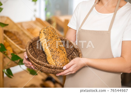 Female hands holding basket with loaf of bread Female hands holding basket with loaf of bread 76544987