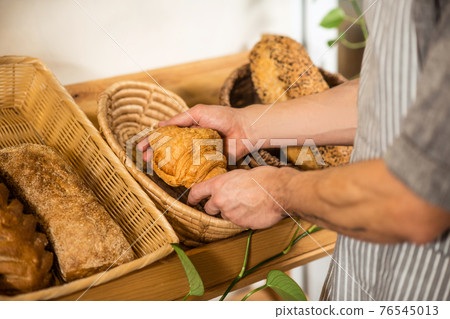 Hands of man stacking bakery products in baskets Hands of man stacking bakery products in baskets 76545013