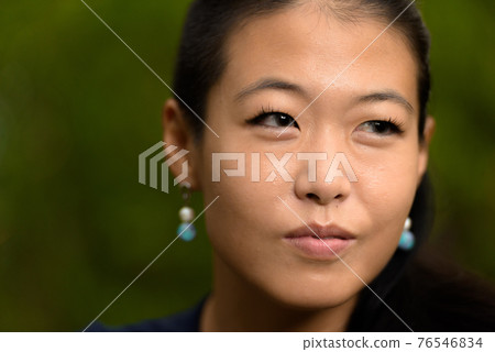 Close-up portrait of beautiful rebel Asian woman face smiling and thinking outdoors Close-up portrait of beautiful rebel Asian woman face smiling and thinking outdoors 76546834