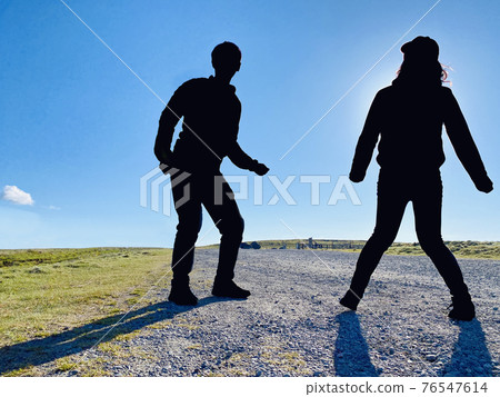 試圖在高原上跳躍的男性和女性剪影 試圖在高原上跳躍的男性和女性剪影 76547614