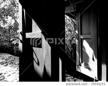 A black and white picture of a wooden window.The sun shines in the window.soft focus. 76548252