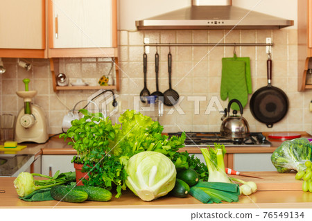 Many green vegetables on kitchen table 76549134