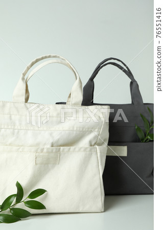 Stylish eco bags and twigs on white background Stylish eco bags and twigs on white background 76551416