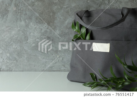 Stylish eco bag with branches against gray textured background Stylish eco bag with branches against gray textured background 76551417