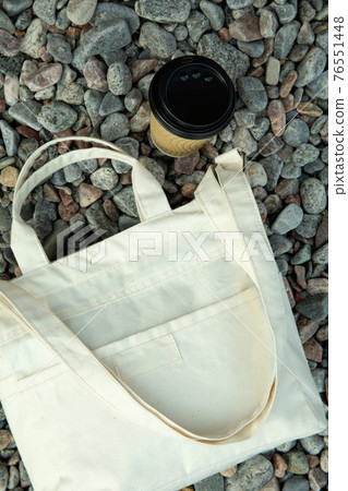 Stylish eco bag and paper cup outdoor on pebbles Stylish eco bag and paper cup outdoor on pebbles 76551448