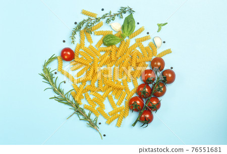 Raw fusilli pasta with tomatoes, herbs and basil. Italian pasta with ingredients in the colors of the Italian flag. 76551681