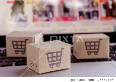 Online shopping. Cardboard box with a shopping cart logo on laptop keyboard. Shopping service on The online web. offers home delivery Online shopping. Cardboard box with a shopping cart logo on laptop keyboard. Shopping service on The online web. offers home delivery 76554456
