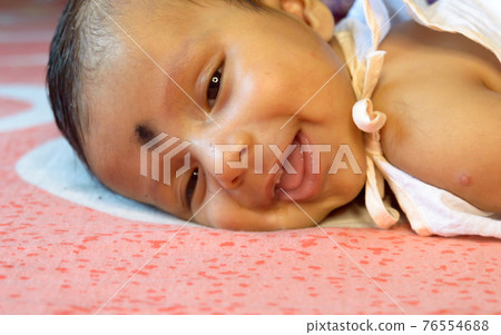 Close up face of cute newborn baby boy in smiling happy mood. One month old Sweet little infant toddler Closeup portrait. Indian ethnicity. Front view. Child care peace tranquil background. Close up face of cute newborn baby boy in smiling happy mood. One month old Sweet little infant toddler Closeup portrait. Indian ethnicity. Front view. Child care peace tranquil background. 76554688