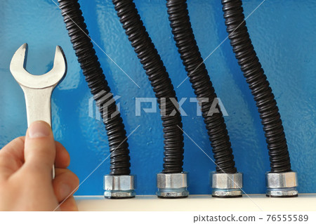 These are power cables in corrugated insulation and a rock electrician with a wrench close up These are power cables in corrugated insulation and a rock electrician with a wrench close up 76555589
