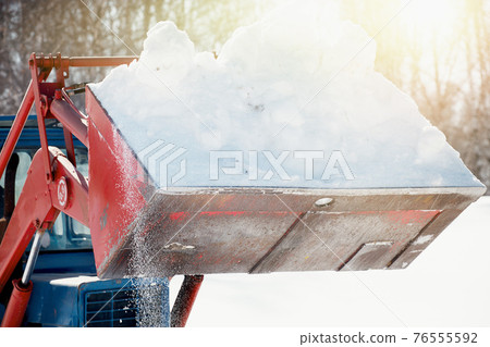 Tractor in a bucket to take out the snow. Clearing the territory from the effects of snowfall. Tractor in a bucket to take out the snow. Clearing the territory from the effects of snowfall. 76555592