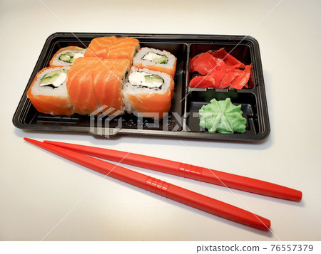 Japanese sushi roll for dinner on an isolated white background. The concept of the delivery of Japanese dishes 76557379