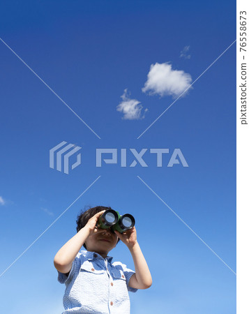 A boy looking through binoculars under the blue sky 76558673
