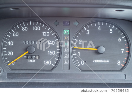 An old analog dashboard of a Japanese car. Speedometer up to 180 km and tachometer up to 8000 rpm 76559485