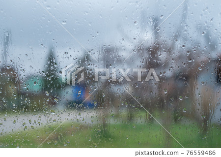 Raindrops on the glass. The background is a blurry image of the street 76559486
