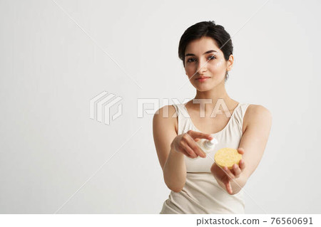 Beautiful brunette in a white T-shirt Sponge in the hands of skin care Beautiful brunette in a white T-shirt Sponge in the hands of skin care 76560691